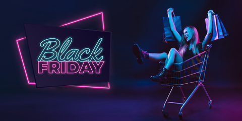 Image showing Portrait of young woman in neon light on dark backgound. The human emotions, black friday, cyber monday, purchases, sales, finance concept. Neoned lettering.