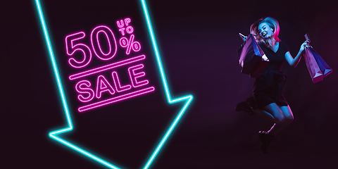 Image showing Portrait of young woman in neon light on dark backgound. The human emotions, black friday, cyber monday, purchases, sales, finance concept. Neoned lettering.