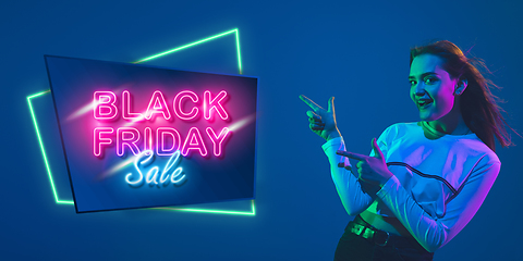 Image showing Portrait of young woman in neon light on blue backgound. The human emotions, black friday, cyber monday, purchases, sales, finance concept. Neoned lettering.