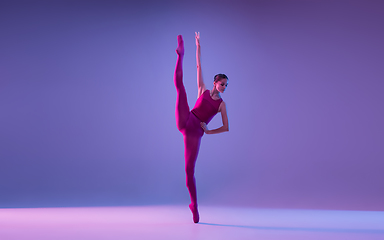 Image showing Young and graceful ballet dancer isolated on purple studio background in neon light