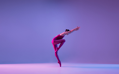 Image showing Young and graceful ballet dancer isolated on purple studio background in neon light