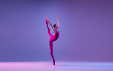 Image showing Young and graceful ballet dancer isolated on purple studio background in neon light