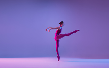 Image showing Young and graceful ballet dancer isolated on purple studio background in neon light