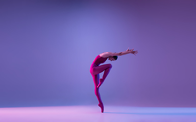 Image showing Young and graceful ballet dancer isolated on purple studio background in neon light