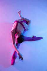 Image showing Young and graceful ballet dancer isolated on purple studio background in neon light