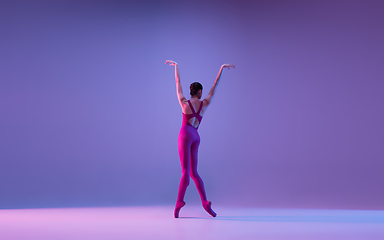 Image showing Young and graceful ballet dancer isolated on purple studio background in neon light