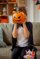 Image showing girl in halloween costume with pumpkin at home