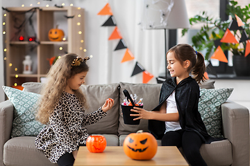 Image showing girls in halloween costumes with candies at home