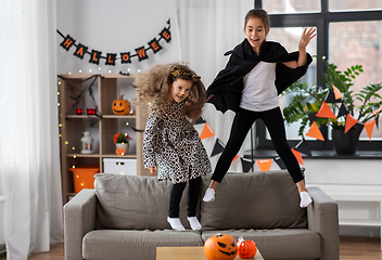 Image showing girls in halloween costumes jumping on sofa