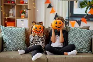 Image showing girls in halloween costumes with pumpkins at home