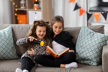 Image showing girls in halloween costumes reading book at home