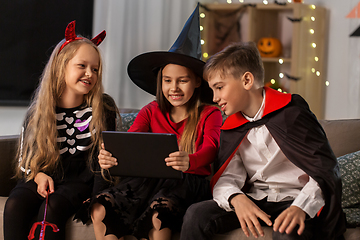 Image showing kids in halloween costumes with tablet pc at home