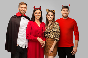 Image showing happy friends in halloween costumes over grey