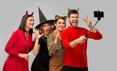 Image showing happy friends in halloween costumes taking selfie