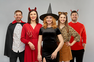 Image showing happy friends in halloween costumes over grey