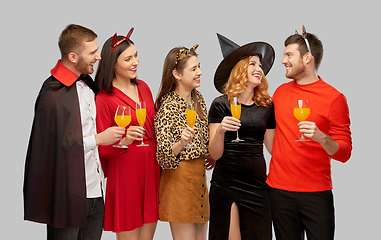 Image showing happy friends in halloween costumes over grey