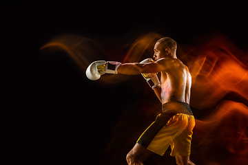 Image showing Professional boxer training isolated on black studio background in mixed light