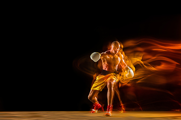 Image showing Professional boxer training isolated on black studio background in mixed light