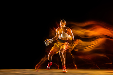 Image showing Professional boxer training isolated on black studio background in mixed light