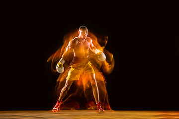 Image showing Professional boxer training isolated on black studio background in mixed light