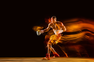 Image showing Professional boxer training isolated on black studio background in mixed light