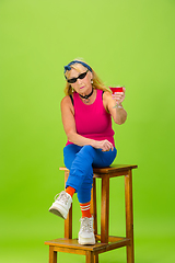 Image showing Senior woman in ultra trendy attire isolated on bright green background