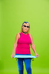 Image showing Senior woman in ultra trendy attire isolated on bright green background