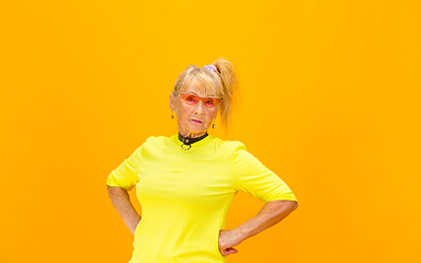 Image showing Senior woman in ultra trendy attire isolated on bright orange background