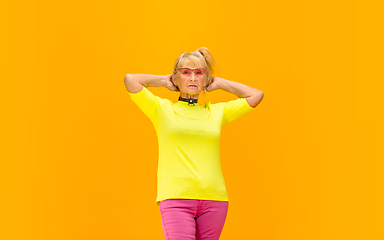 Image showing Senior woman in ultra trendy attire isolated on bright orange background