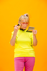 Image showing Senior woman in ultra trendy attire isolated on bright orange background