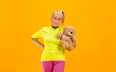 Image showing Senior woman in ultra trendy attire isolated on bright orange background