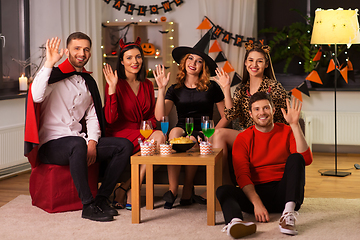 Image showing happy friends in halloween costumes at home party