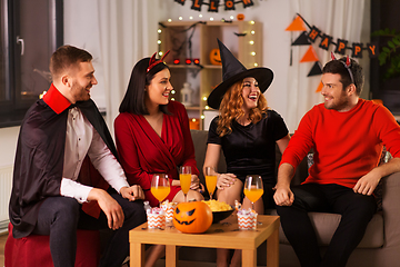 Image showing happy friends in halloween costumes at home party