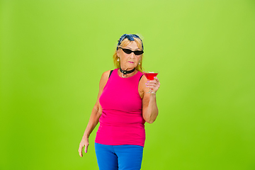 Image showing Senior woman in ultra trendy attire isolated on bright green background
