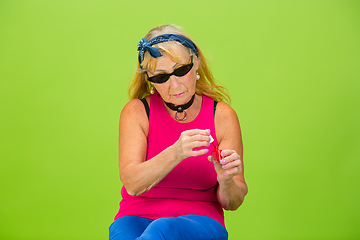 Image showing Senior woman in ultra trendy attire isolated on bright green background