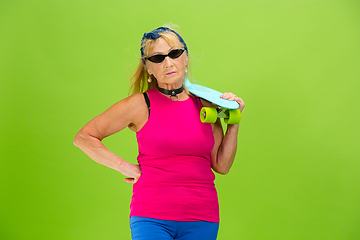 Image showing Senior woman in ultra trendy attire isolated on bright green background