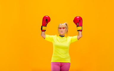 Image showing Senior woman in ultra trendy attire isolated on bright orange background