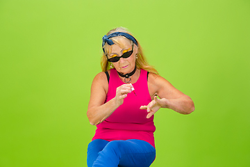 Image showing Senior woman in ultra trendy attire isolated on bright green background