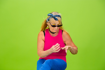 Image showing Senior woman in ultra trendy attire isolated on bright green background