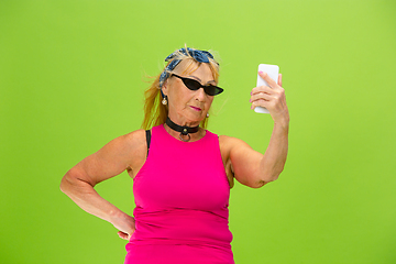 Image showing Senior woman in ultra trendy attire isolated on bright green background