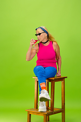 Image showing Senior woman in ultra trendy attire isolated on bright green background