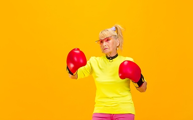 Image showing Senior woman in ultra trendy attire isolated on bright orange background