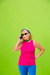 Image showing Senior woman in ultra trendy attire isolated on bright green background