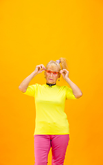 Image showing Senior woman in ultra trendy attire isolated on bright orange background