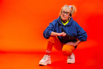 Image showing Senior woman in ultra trendy attire isolated on bright orange background