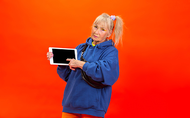 Image showing Senior woman in ultra trendy attire isolated on bright orange background