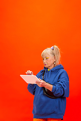 Image showing Senior woman in ultra trendy attire isolated on bright orange background