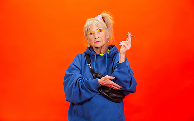 Image showing Senior woman in ultra trendy attire isolated on bright orange background