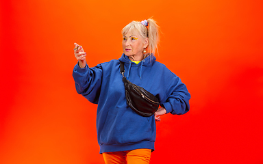 Image showing Senior woman in ultra trendy attire isolated on bright orange background