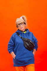 Image showing Senior woman in ultra trendy attire isolated on bright orange background